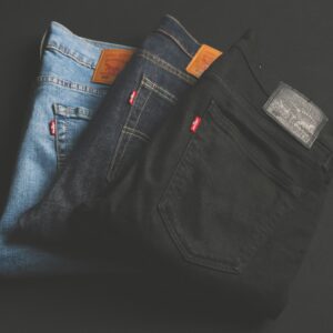 A stack of blue, dark, and black denim jeans folded on a dark surface.