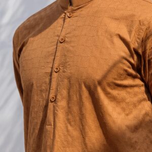 A detailed view of a brown men's kurta with intricate patterns, captured outdoors in bright daylight.